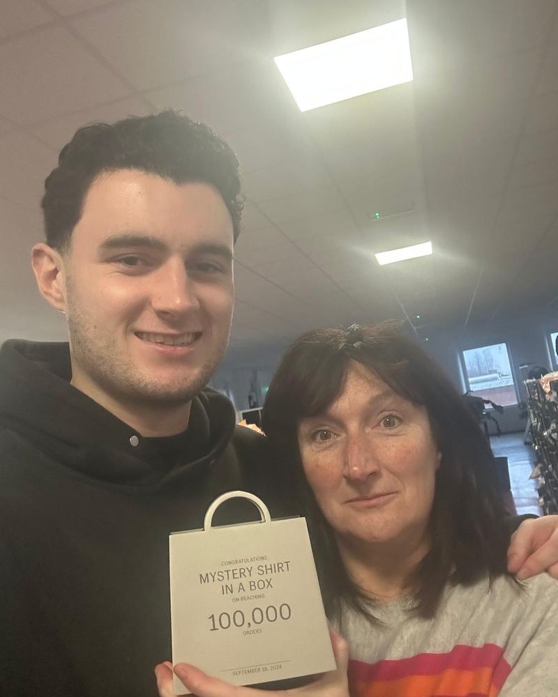 Rory and his mom holding a 100,000 orders plaque